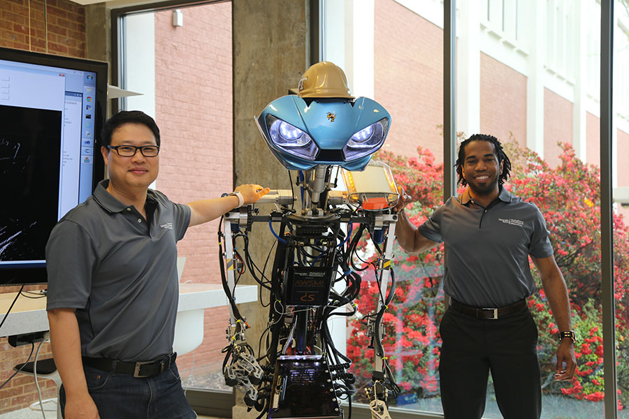 Associate Professor Yong Cho, left, and Dimitri Seneca Snowden pose with the robot Snowden built to help teach underprivileged children about robotics and inspire them to chase their dreams. Snowden has donated the machine to Cho's Robotics and Construction Automation Laboratory. (Photo: Jess Hunt-Ralston)