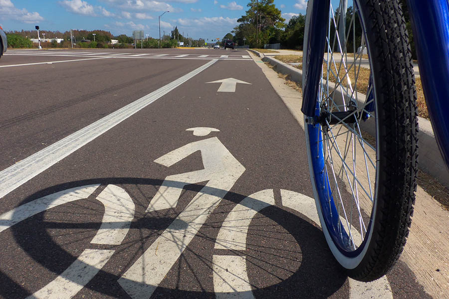 A bicyclist rides in a marked bike lane alongside a multi-lane road in Lutz, Florida. A new study of bicycle infrastructure from a team of School of Civil and Environmental Engineering researchers has found we don’t know much yet about how well bicycle infrastructure like these lanes protect riders. (Photo Courtesy: Daniel Oines via Flickr.)
