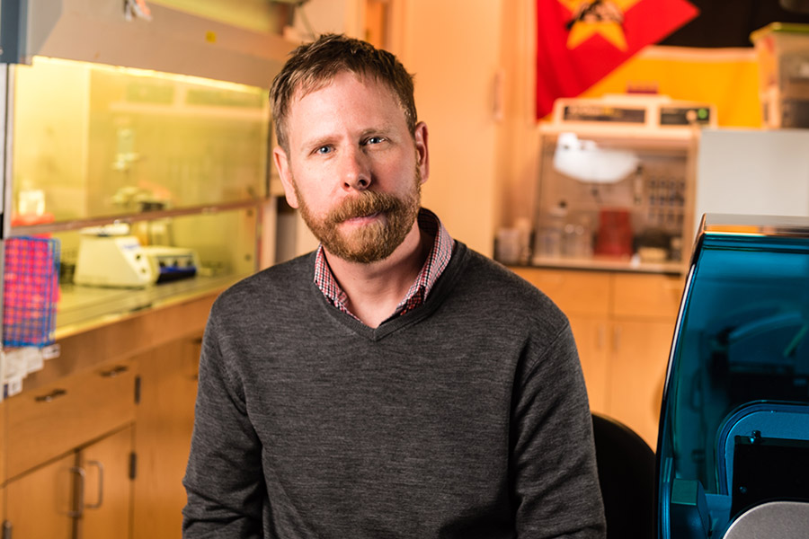 Joe Brown sits in his lab with a fume hood in the background.