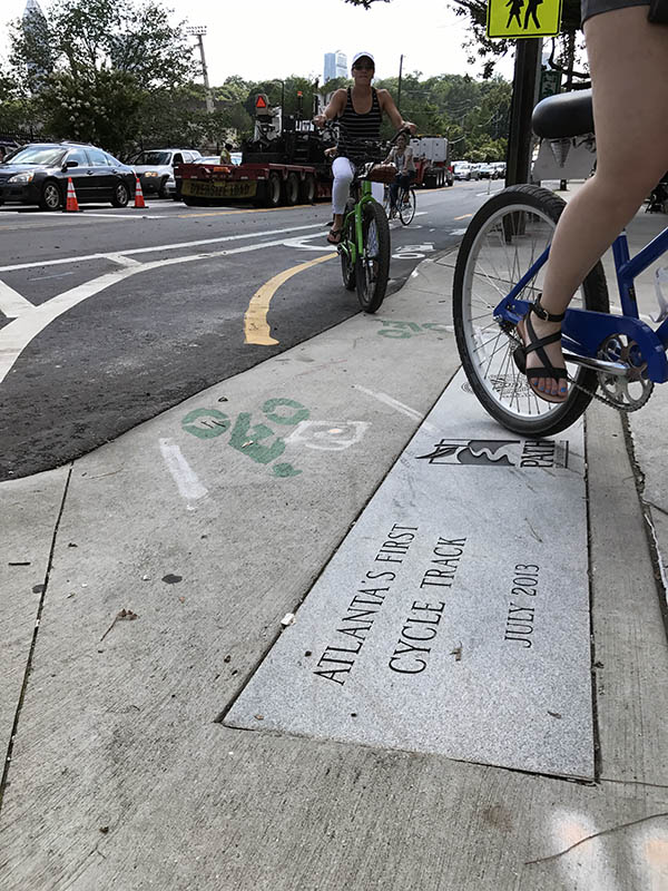 Riders exit the cycle track along 10th Street in Midtown Atlanta near Piedmont Park, turning onto Monroe Drive. The track provides a physical barrier between two-way bicycle traffic and vehicles. (Photo: Jess Hunt-Ralston)