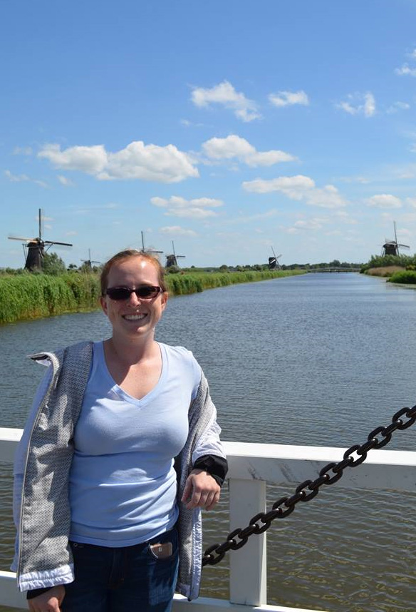 Ph.D. student April Gadsby stands on a bridge over a canal in the Netherlands in 2017 with a few of the country's famed windmills in the background. (Photo Courtesy: April Gadsby)