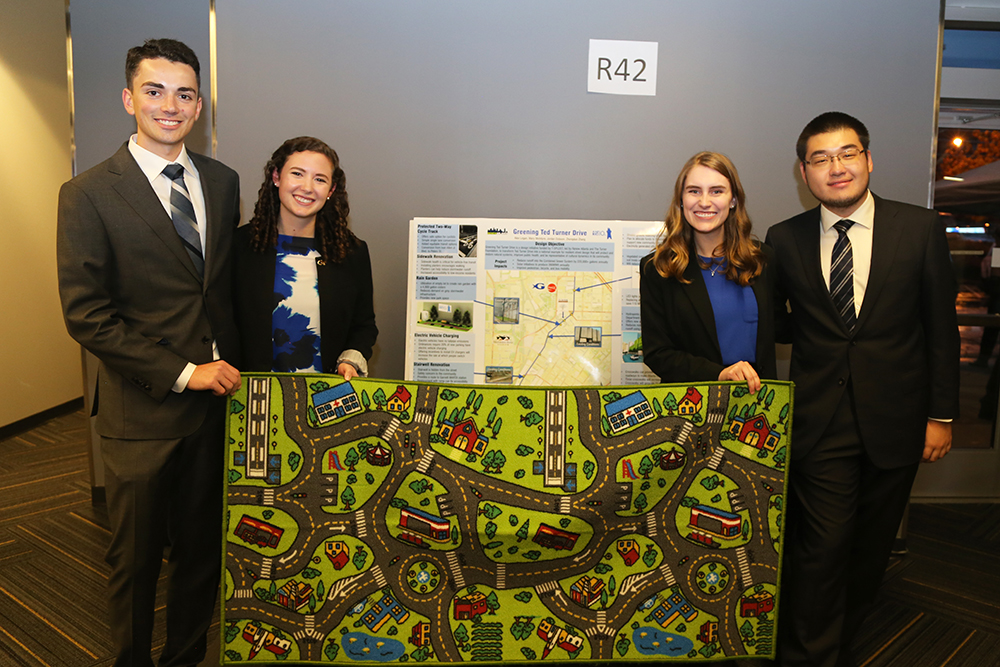 Team Artio LLC — from left, Jordan Dobson, Alexandra Logan, Mary McIntyre and Zhongduo "Frank" Zhang — with the road play mat they used to attract people at the Capstone Design Expo Dec. 5. They developed a dozen different ways to reinvigorate Ted Turner Drive in downtown Atlanta, from protected cycle tracks to innovative new technologies like solar crosswalks. (Photo: Jess Hunt-Ralston)