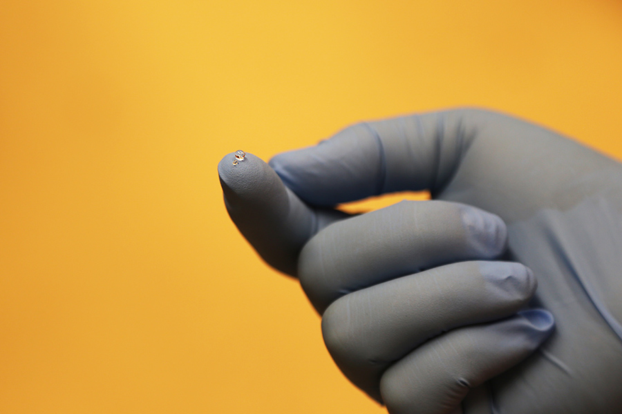 An example of the super-absorbent polymer beads Xing Xie is developing to improve the results of diagnostic tests on biological samples. Two beads are sitting on the fingertip: a dry bead roughly 500 micrometers in diameter and one that has absorbed water and grown dramatically. (Photo: Jess Hunt-Ralston)