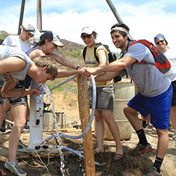 Group of students drinking water from a well