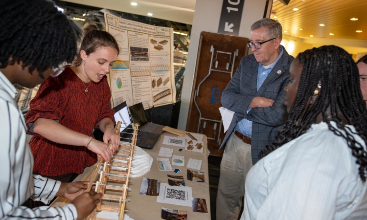 Timeless Consulting Solutions demonstrates the design of their lattice truss bridge to school chair Don Webster.