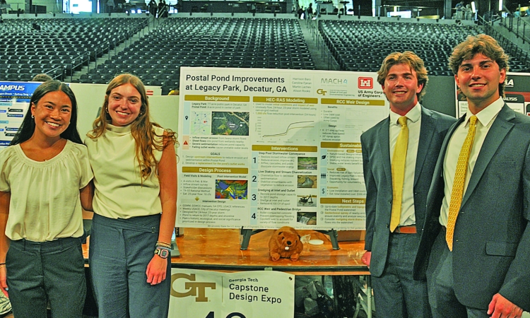 Two young women and two young men pose in front of their Capstone Design project