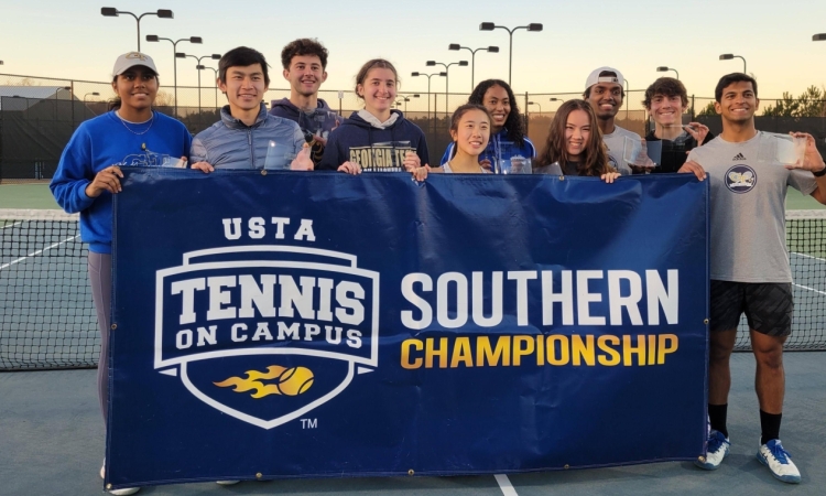 A group of people poses behind a banner that said USTA Tennis on Campus Southern Championship 