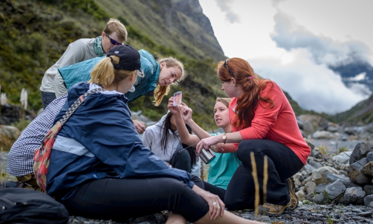 A group of students by a mountain looks at results of a water quality test