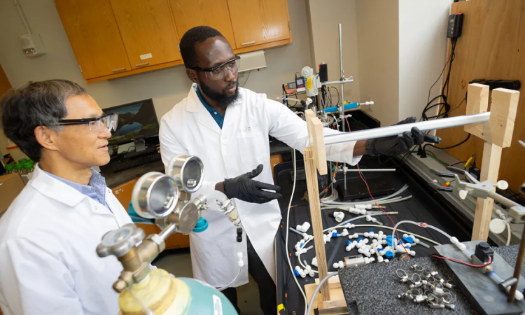Two men in protective eyeglasses and white lab coats working in a lab 