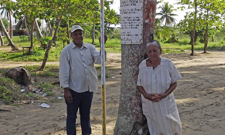 Claudio Martinez from the Dominican Republic’s Oficina Nacional de Meteorologia in Matancitas with local resident Patria, right, who took Martinez and Georgia Tech’s Hermann Fritz back to the site of a 1946 tsunami in the area. Patria remembered how high waters had reached at this palm tree, helping the team reconstruct the tsunami’s impacts more than seven decades after it happened. (Photo Courtesy: Hermann Fritz)