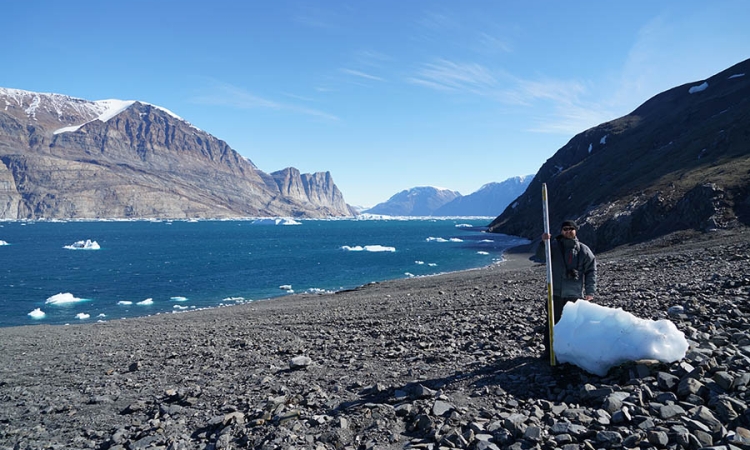 University of Oregon volcanologist Thomas Giachetti stands with an iceberg washed ashore by a landslide-generated tsunami in Greenland in June. (Photo: Hermann Fritz)