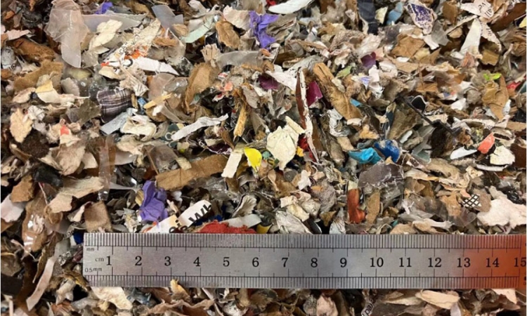 A silver ruler in the lower third of the photograph provides scale for small pieces of municipal solid waste