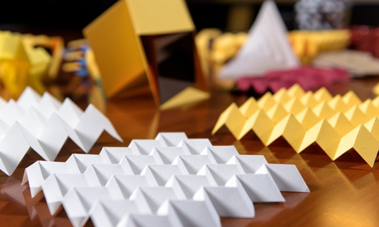 Paper origami models demonstrate various folding patterns that can be useful in engineering applications. In the foreground is a sheet in the Miura-ori pattern. (Photo: Rob Felt)