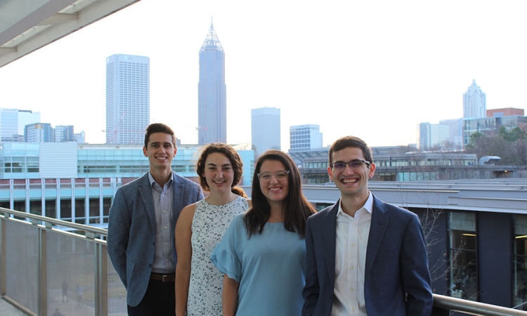 The four members of the student team River Recon pose in front of the Atlanta skyline