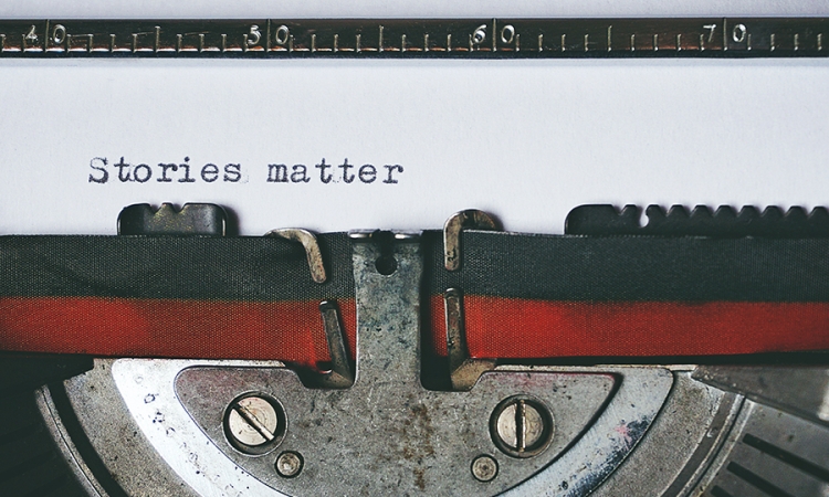 A close up view of a typewriter ribbon with with the words "Stories Matter" typed on a piece of white paper