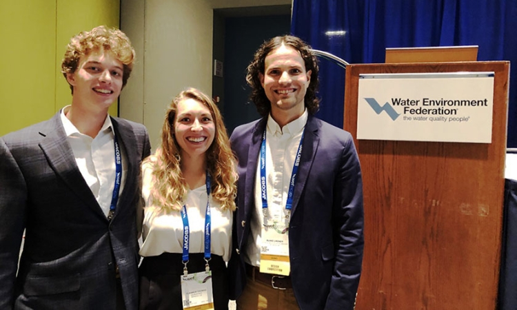 Three Georgia Tech students stand by the podium at the Water Environment Federation's student design competition