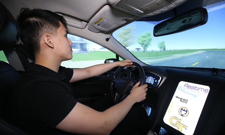 Ph.D. student Anye Zhou drives the new full-size simulator in Srinivas Peeta’s lab. The simulator is built from a 2013 Ford Focus and includes wraparound screens to immerse test drivers in the simulated environment. (Photo: Candler Hobbs)