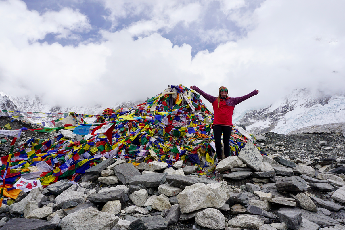 Person standing with a pile of flags at everest base camp