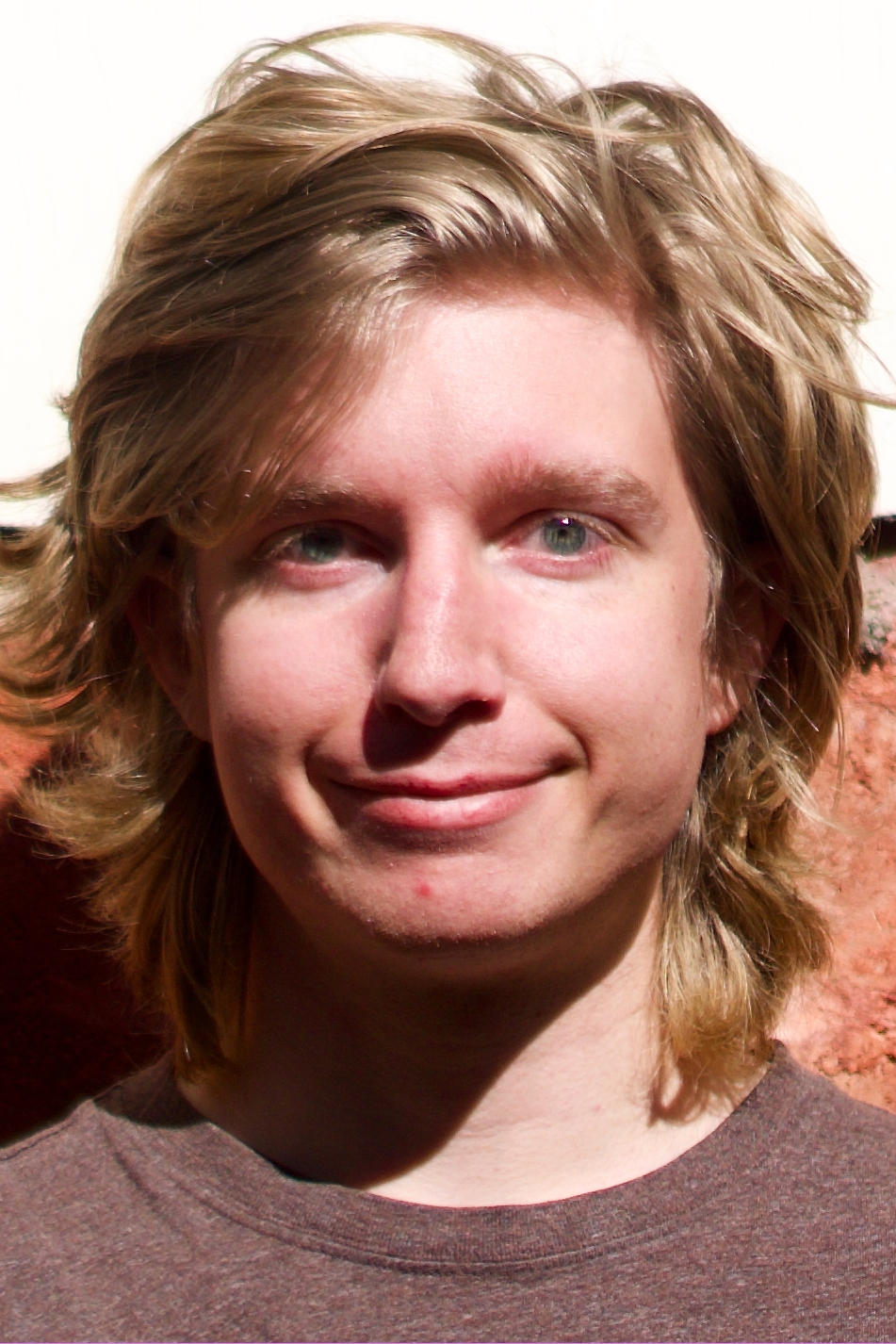 Blond man in front of brick wall