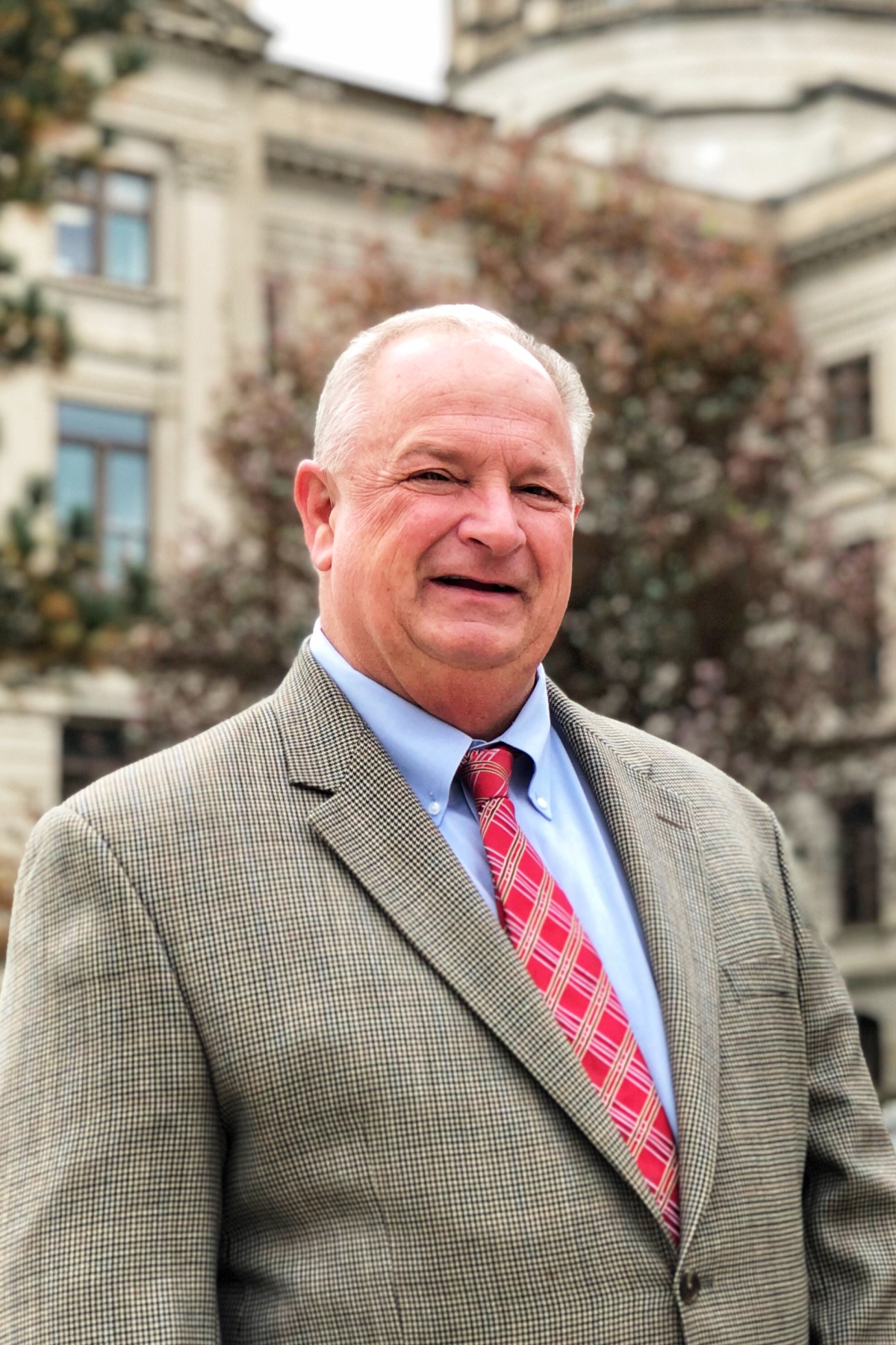 Headshot of man in suit in front of the State of Georgia Capitol building