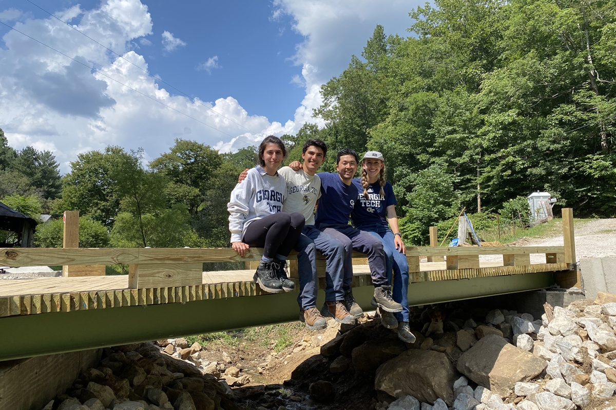 four students sitting on a bridge