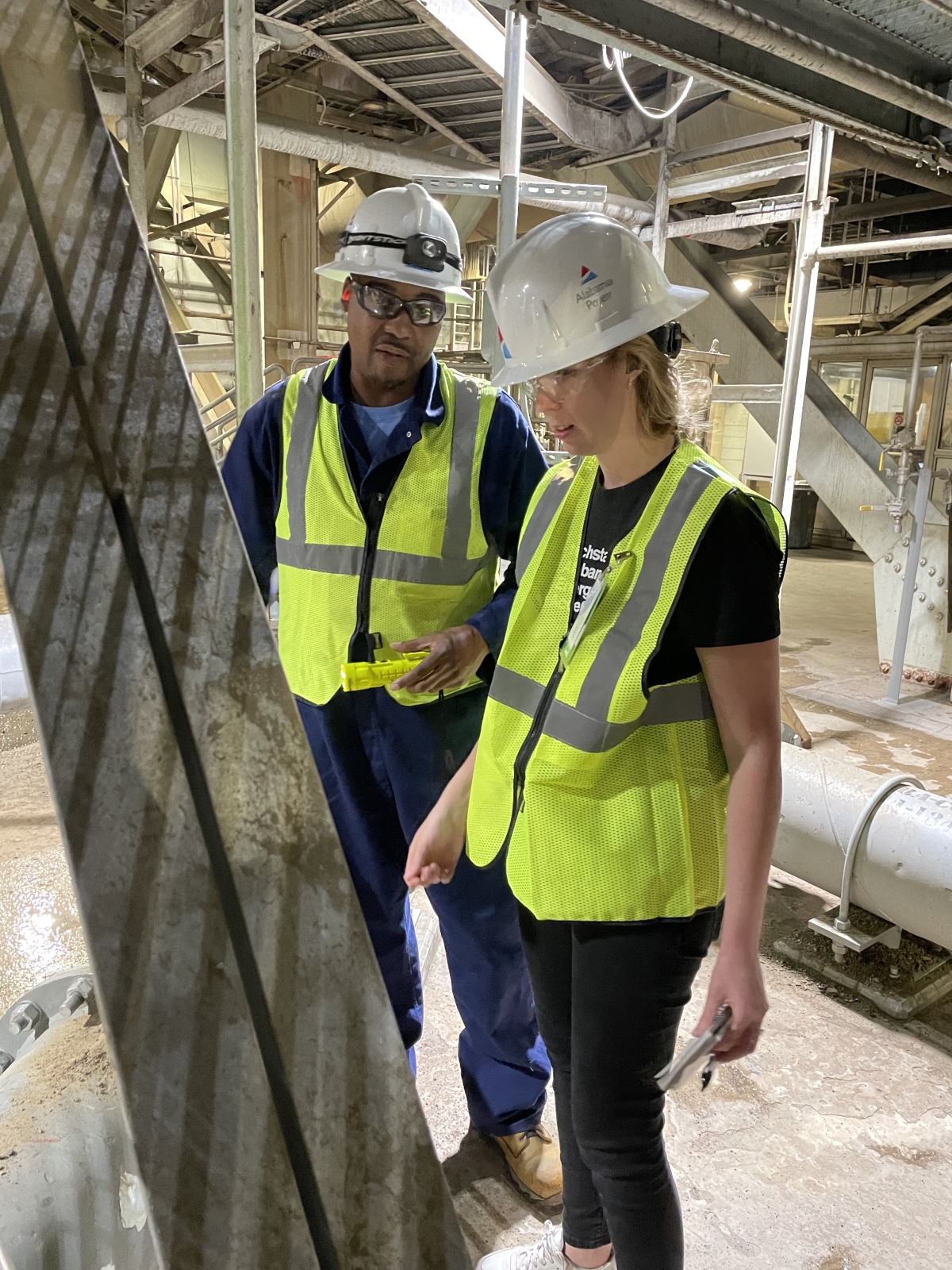 Two people in hardhats and vests at a power plant