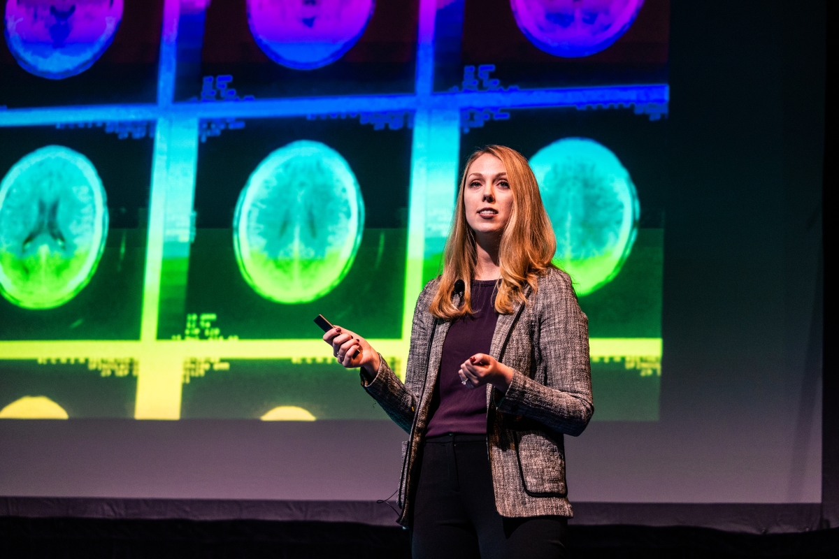 A woman standing in front of a colorful projection 