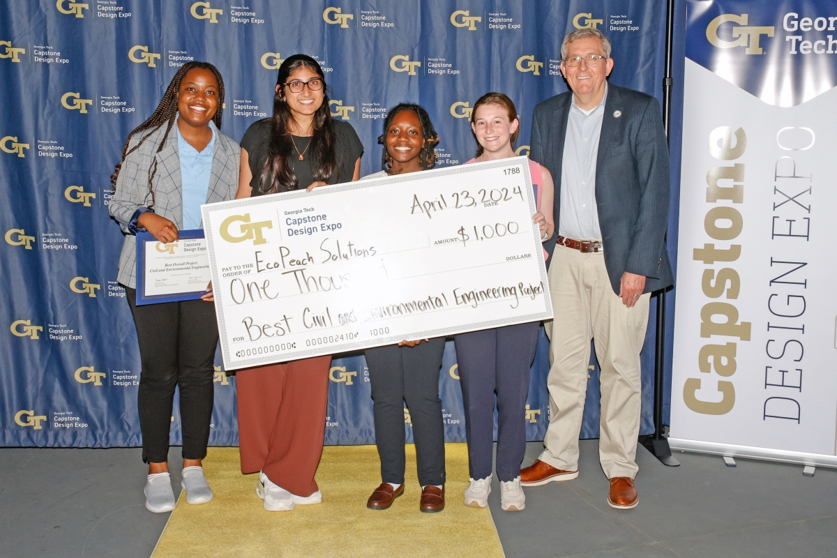 The EcoPeach Solutions team poses with an oversized check 