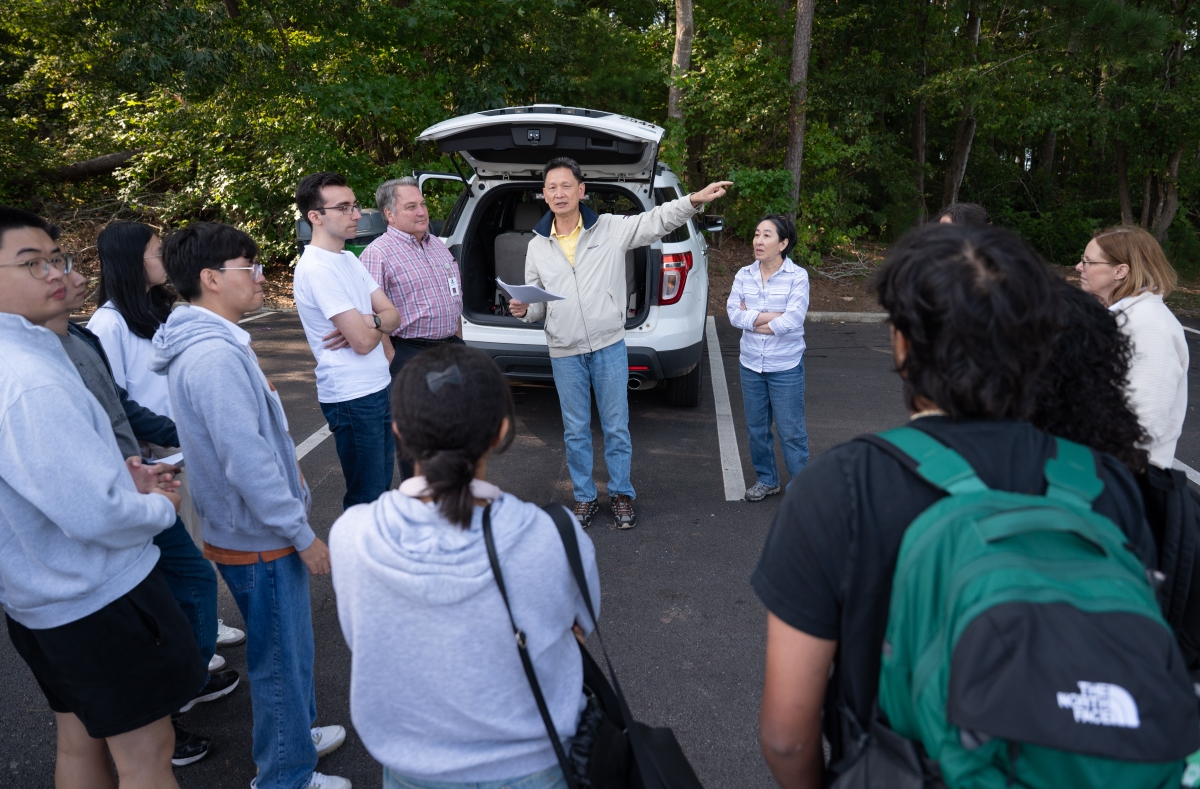 A man gives direction to a group of people in a parking lot