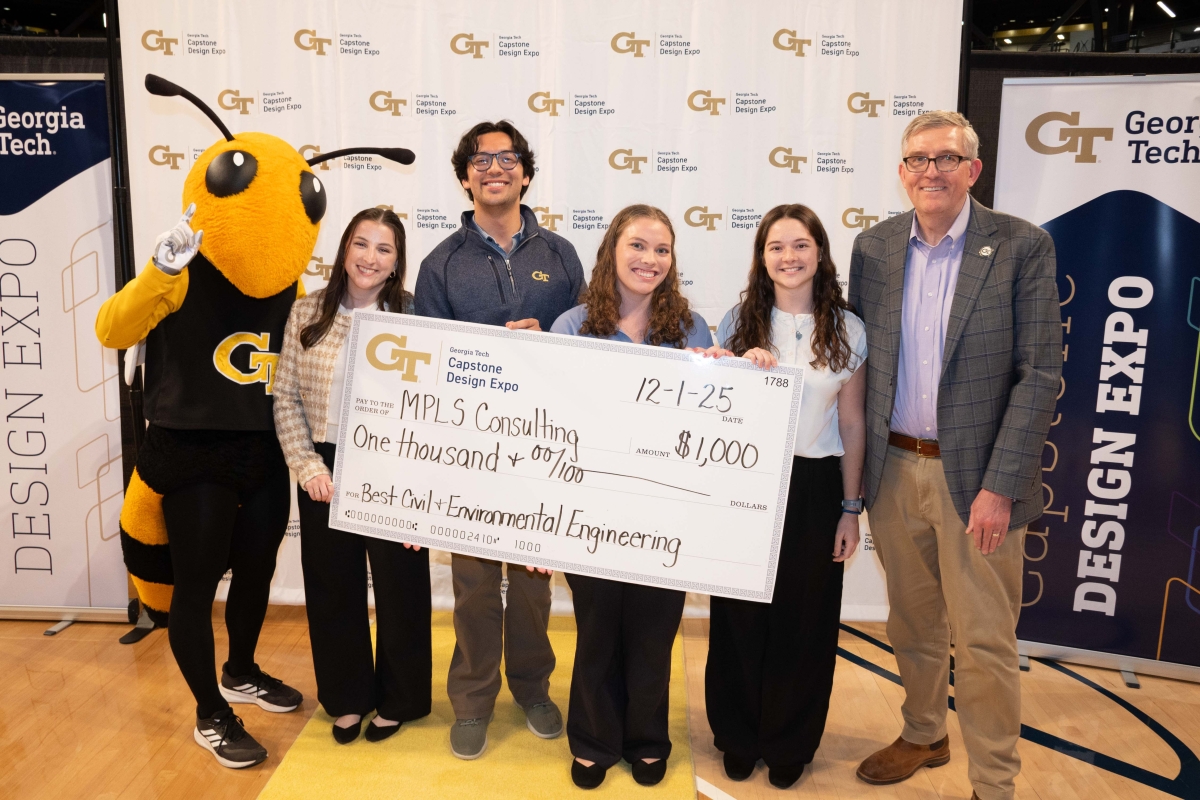 A Yellow Jacket mascot poses with a group of people holding an oversized prize check 
