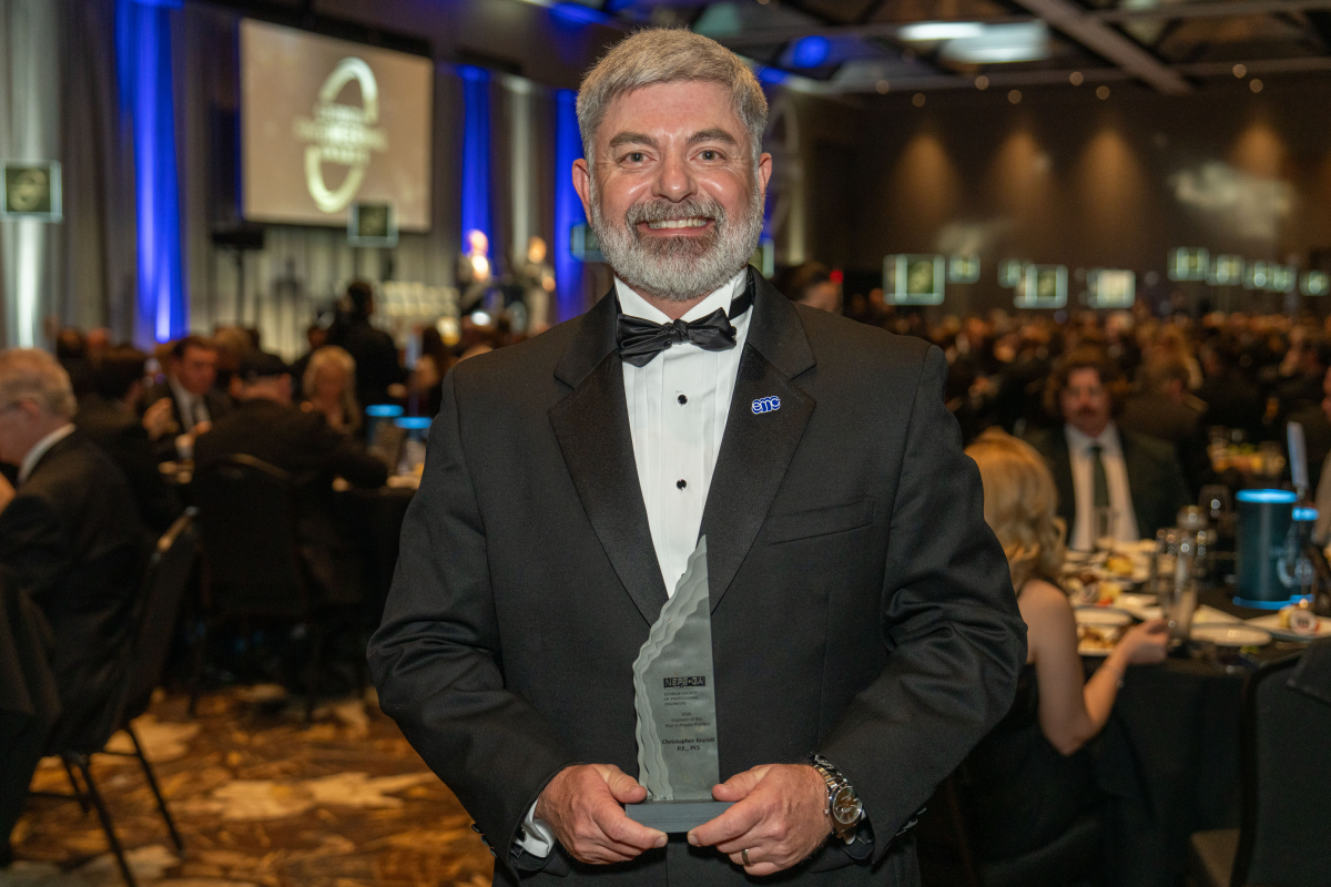 A man in a tuxedo holds an award 