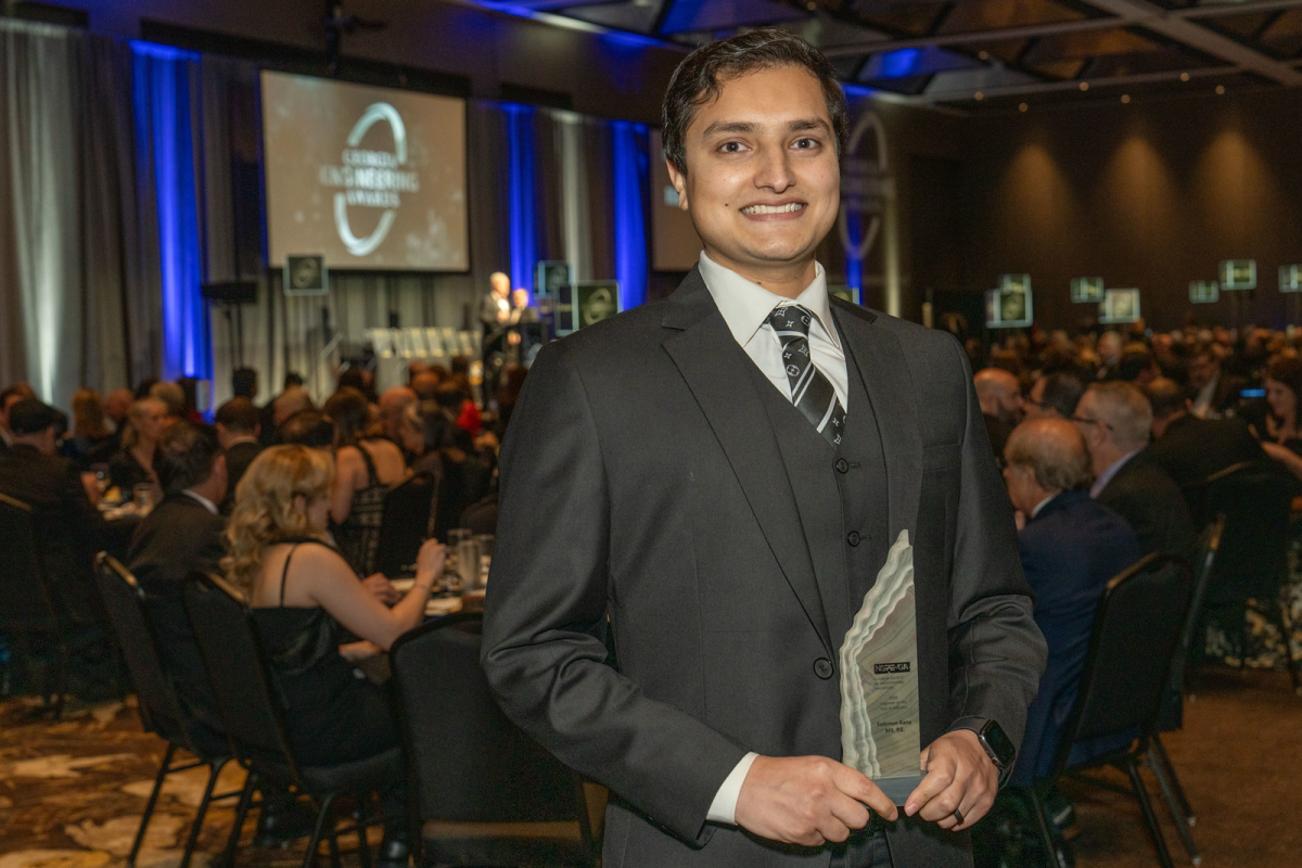 A man in a suit holds an award 