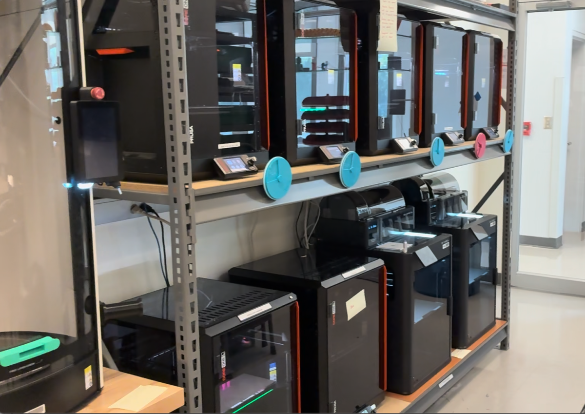 3D printers on two shelves of an industrial shelving unit