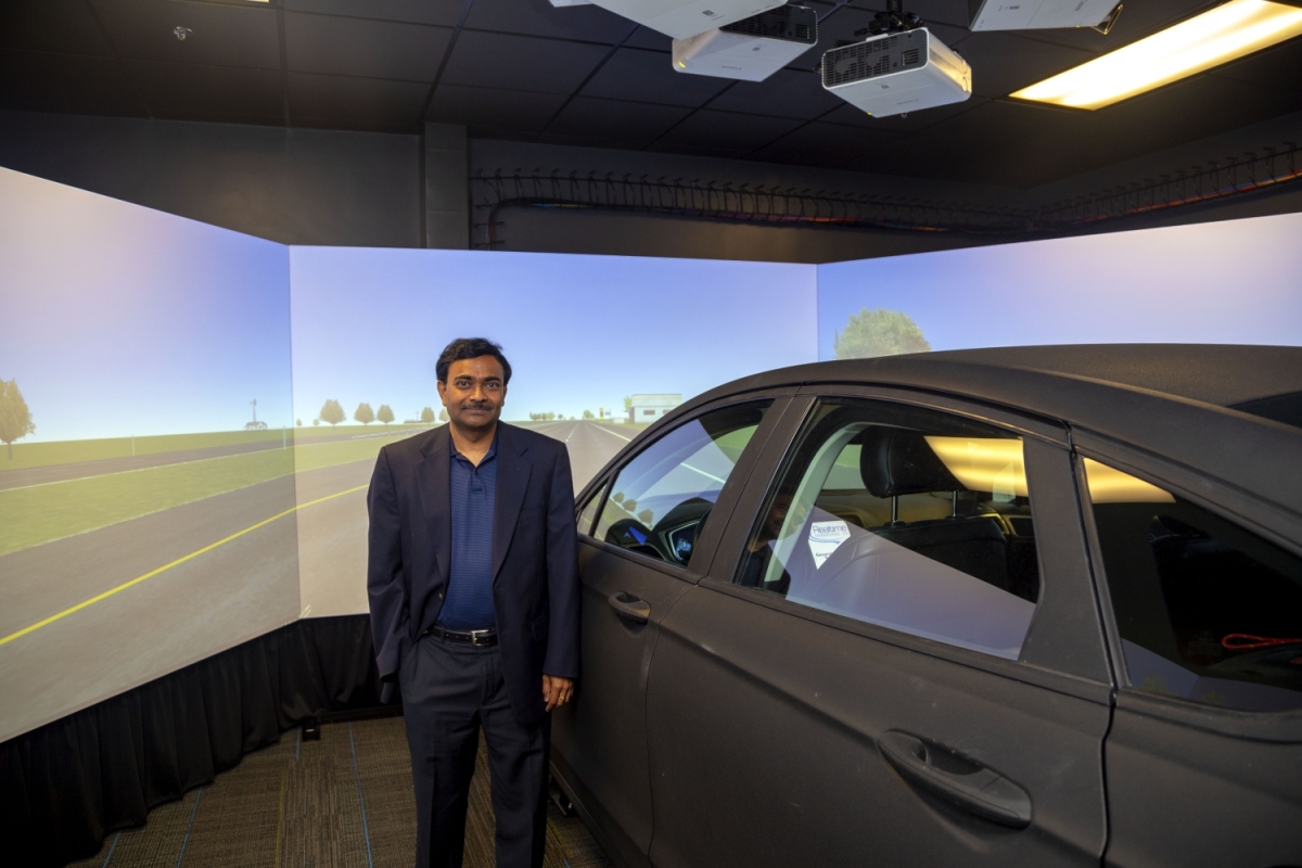 Srinivas Peeta stands next to the driving simulator in his lab