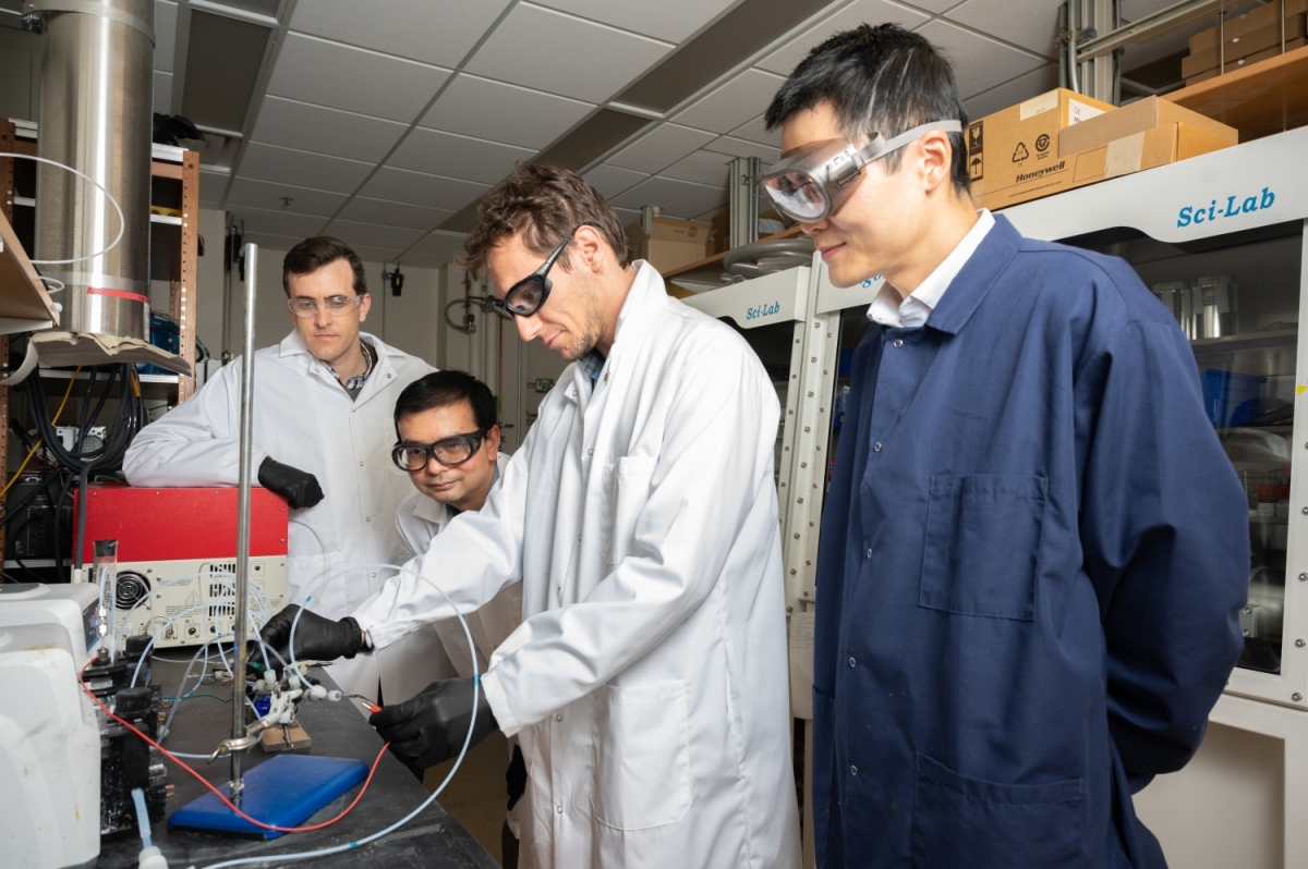 Four men wearing protective equipment working in a laboratory