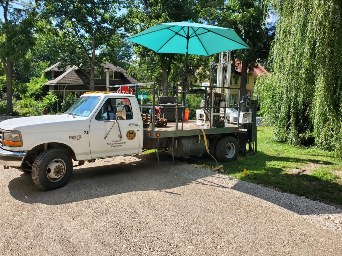 A truck with an umbrella and equipment on the flat bed.