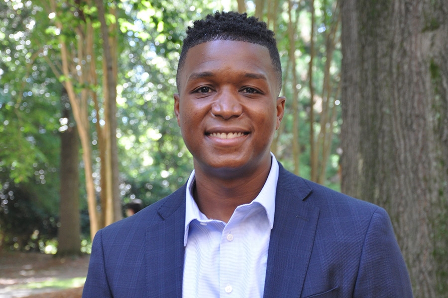 A smiling man in front of trees
