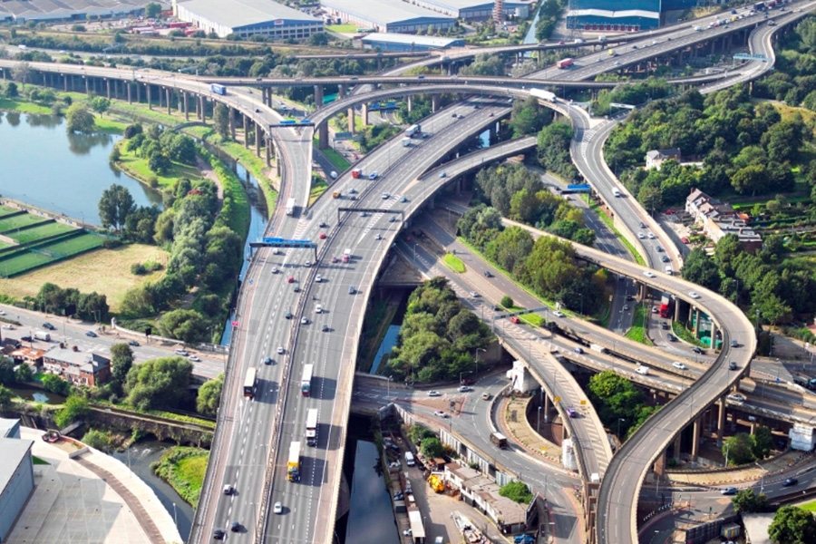 Cars and trucks drive on an interchange with roads branching off in several directions.