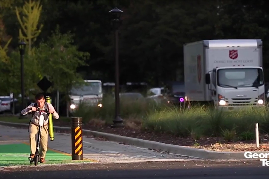 Screenshot of North Avenue Smart Corridor: One Year Later video, with student riding a scooter on separated bike path and traffic in vehicle lanes.