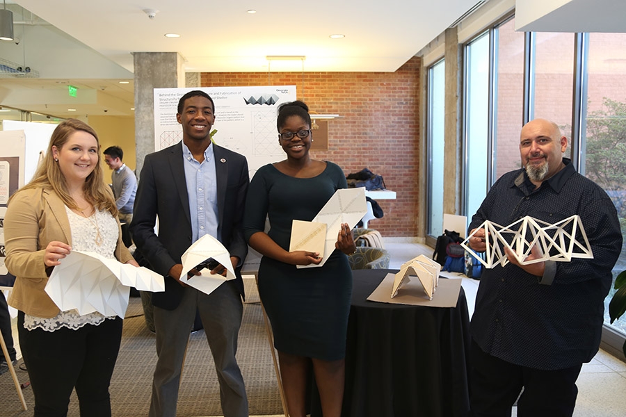 The Yoshi Group used a single Miura-ori based Yoshimura origami pattern to design four unique structures. From left, Phoebe Edalatpour, Jared Williams, Maria Yagnye and Emanuel Ferro hold models of their designs. (Photo: Jess Hunt-Ralston)