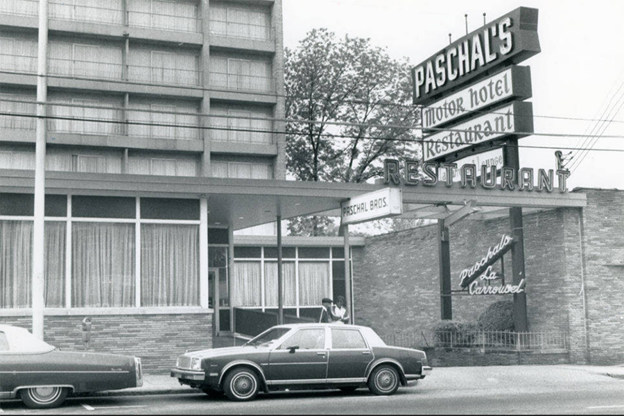 A black and white vintage photo of cars parked in front of the marquee sign for Paschal's Motor Hotel and Restaurant 