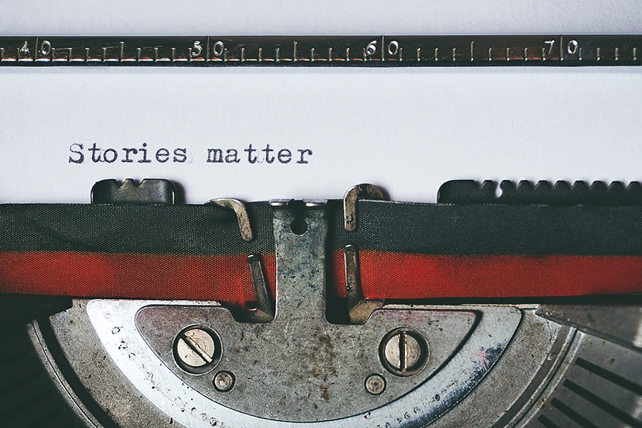 A close up view of a typewriter ribbon with with the words "Stories Matter" typed on a piece of white paper