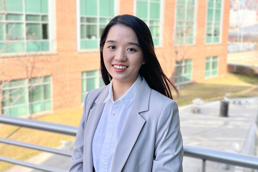 Wensi Chen poses in front of a brick building for a portrait