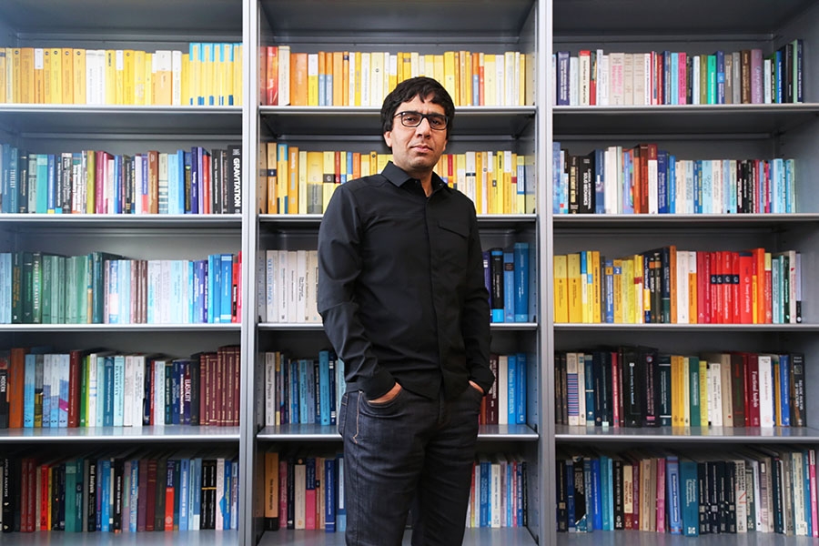 Arash Yavari stands in front of shelves stacked with colorful books