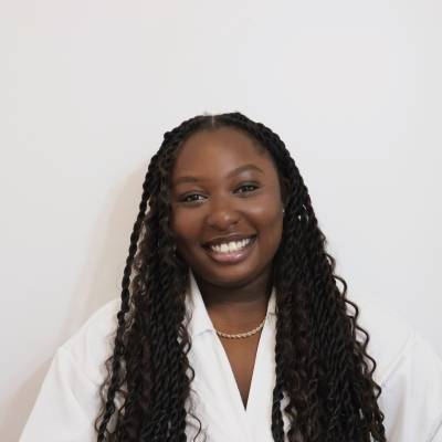 Portrait of Kathryn Owusu in a white blouse with a gold necklace