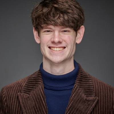 Jackson Stewart wearing a blue turtleneck and a brown corduroy blazer