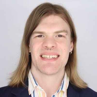Portrait of Gavin Brahney in a mult-colored striped collared shirt and a blue jacket
