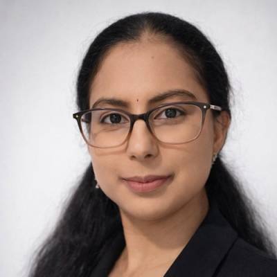 Portrait of Sravani Ambapudi wearing glasses and a black blazer
